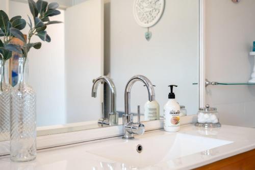 a bathroom sink with two faucets and a mirror at Little Big House - Rotorua Holiday Home in Rotorua