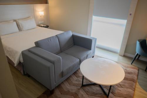 a bedroom with a bed and a couch and a table at Swiss-Belinn Saripetojo Solo in Solo