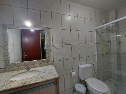 y baño con aseo, lavabo y espejo. en Apartamento 12 - Bombinhas - 200 metros da praia, en Bombinhas