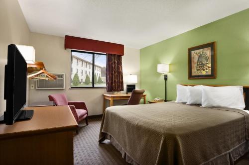 a hotel room with a bed and a flat screen tv at Travelodge by Wyndham Battle Creek in Battle Creek
