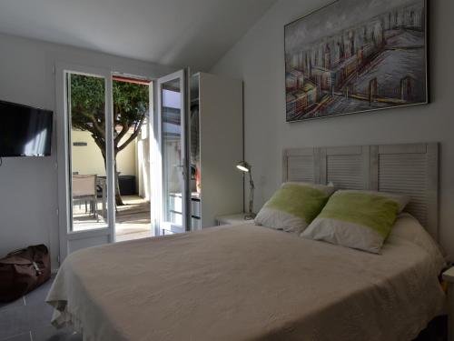 une chambre avec un lit avec un tableau sur le mur dans l'établissement T2 bis rénové à Arcachon centre avec 2 terrasses, clim, parking, proche plage et gare. - FR-1-420-84, à Arcachon