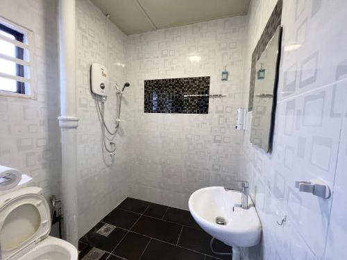een witte badkamer met een wastafel en een toilet bij G East Ipoh Garden Guesthouse in Ipoh