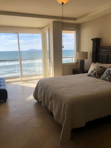 a bedroom with a bed and a view of the ocean at Playa Bonita Rosarito in Rosarito