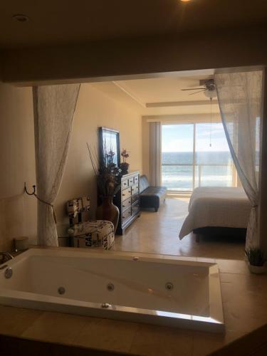 a large bath tub in a room with a bedroom at Playa Bonita Rosarito in Rosarito