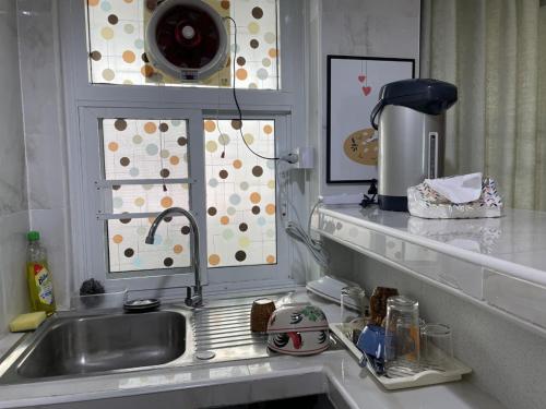eine Küchentheke mit einem Waschbecken und einem Fenster in der Unterkunft APARTMENT A4 DINDAENG in Bangkok