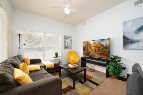 a living room with a couch and a tv at Pet Friendly House in Resort Style Condo Near Disney, 4 Pools, Hot Tub & Gym in Kissimmee