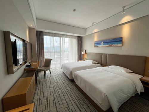 a hotel room with two beds and a flat screen tv at Guangzhou Nanhong Ausotel Hotel in Guangzhou