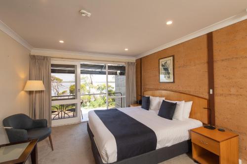 a bedroom with a bed and a chair and a window at Mercure Kangaroo Island Lodge in American River