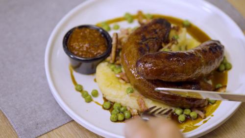 a plate of food with sausage and green peas at The Cavenagh in Darwin