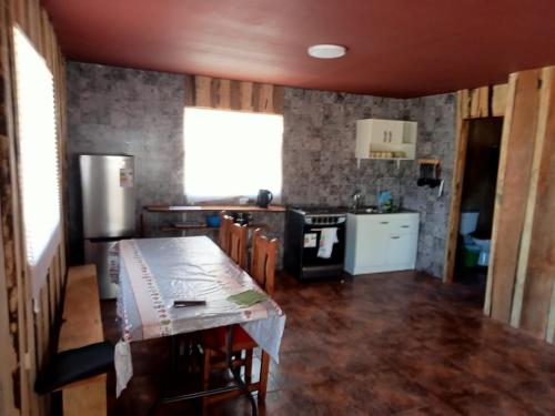 a kitchen with a table with chairs and a refrigerator at Cabaña Cunco parcela in Cunco