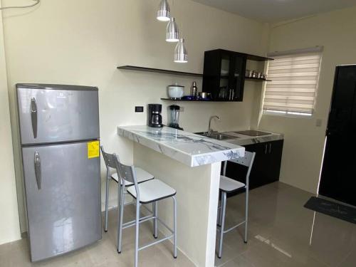 a kitchen with a stainless steel refrigerator and chairs at Hermosa suite privada y cerca de todo in Guayaquil