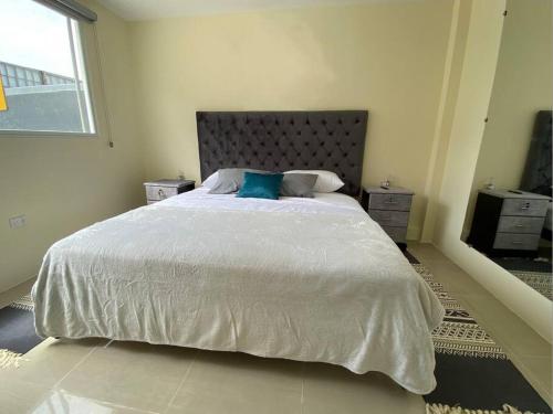 1 dormitorio con cama blanca grande y almohada azul en Hermosa suite privada y cerca de todo, en Guayaquil