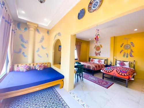 a room with two beds and a table in it at La Reina Maroc Hotel ปากช่อง เขาใหญ่ in Pak Chong