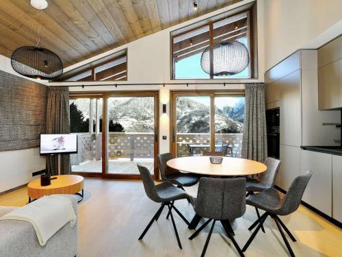 - un salon avec une table, des chaises et une grande fenêtre dans l'établissement Appartement moderne à Courchevel Le Praz, proche des pistes avec parking et wifi - FR-1-568-31, à Courchevel