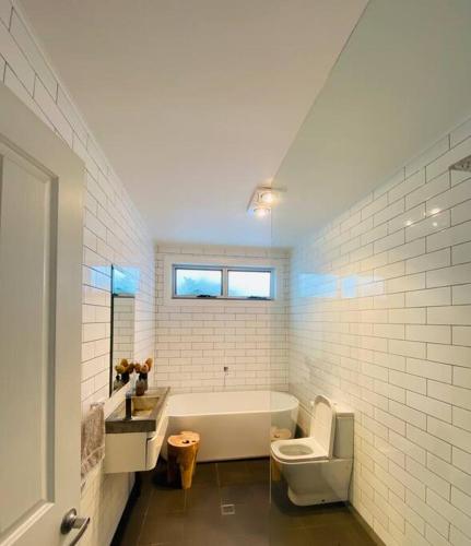 a bathroom with a tub and a toilet and a sink at The Cottage on Market in Mudgee