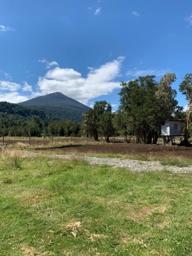 a field with a mountain in the background at Cabaña del campo in Hornopiren