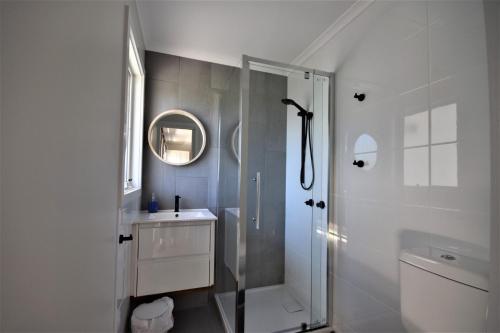 a white bathroom with a shower and a sink at Esplanade Sophistication Close To Town And Inlet Beach in Inverloch