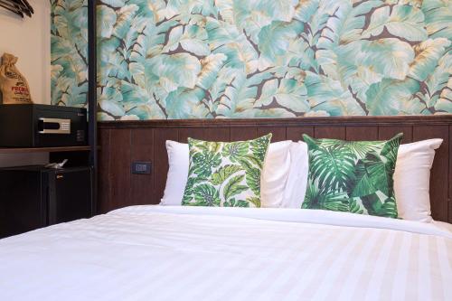 a bed with green and white pillows in a bedroom at FOODOTEL in Bangkok