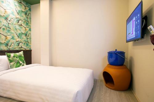 a bedroom with a bed and a flat screen tv at FOODOTEL in Bangkok