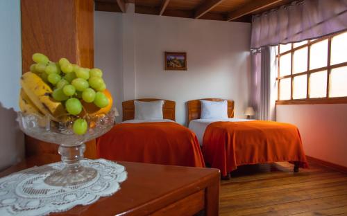 Habitación con 2 camas y un bol de fruta en una mesa. en Centenario Inn, en Cusco
