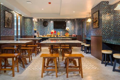 a restaurant with wooden tables and chairs and a bar at FOODOTEL in Bangkok