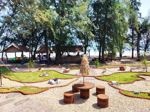 Mumsa Beach Resort & Restaurant في بانهوايْ يانغْ: حديقة فيها جلسة وطاولة وبعض الأشجار
