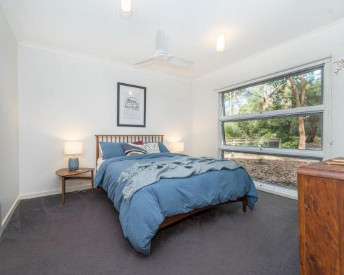 een slaapkamer met een groot bed en een raam bij Leafy Beach Retreat in Inverloch