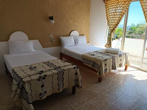 a hotel room with two beds and a window at Hotel Casa Juanita in Puerto Escondido