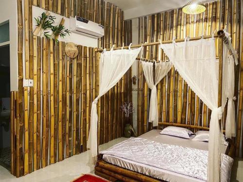 ein Schlafzimmer mit einem Himmelbett in einer Bambusmauer in der Unterkunft Bí Đỏ homestay in Tuy Hoa
