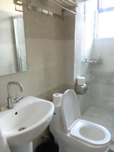 a white bathroom with a toilet and a sink at Smarts residence in Nairobi