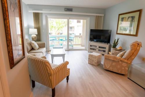 sala de estar con sillas, TV y mesa en Four Winds F8 condo, en St. Augustine