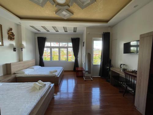 a bedroom with two beds and a desk and window at CaLi Nguyen in Da Lat