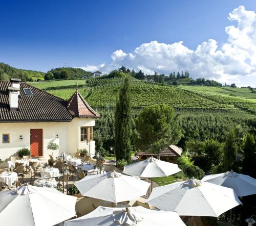a restaurant with white umbrellas in front of a vineyard at Hotel Spitaler in Appiano sulla Strada del Vino