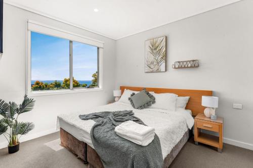 a white bedroom with a bed and a window at Bayvista at Silverwater in San Remo