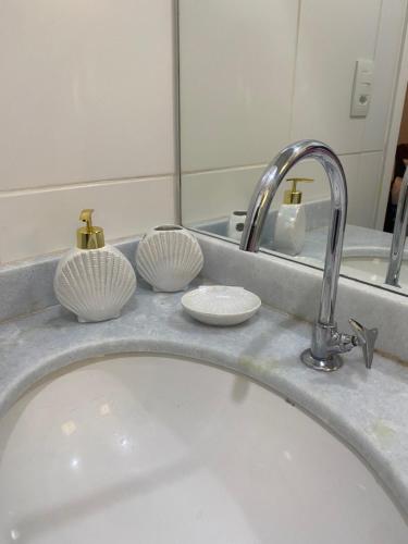 a bathroom sink with two cups and a faucet at Reserva do Sahy-Mangaratiba Condado Loft Sol & Sal in Mangaratiba
