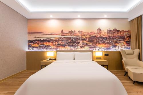 a bedroom with a large bed and a painting on the wall at Joy Fall Hotel in Jiaozhou