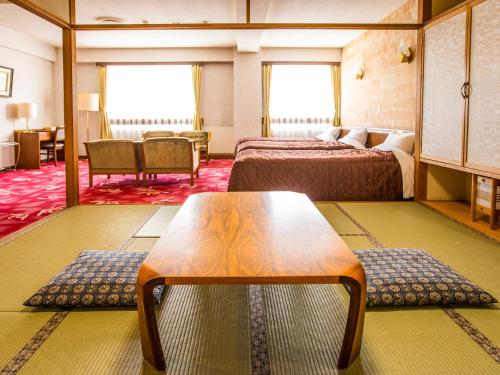 a hotel room with two beds and a table at Kurohime Rising Sun Hotel in Shinano