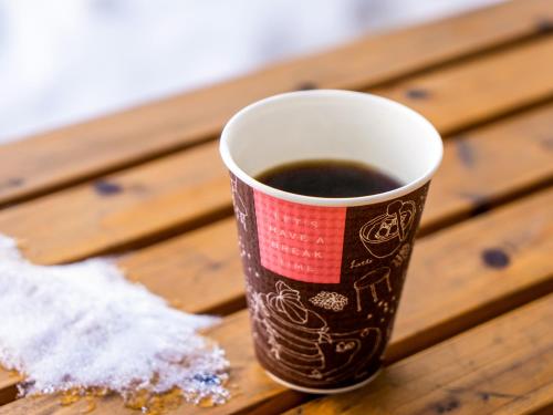 a cup of coffee sitting on a wooden table at Kurohime Kogen Hotel in Shinano