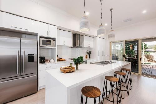 a kitchen with white cabinets and stainless steel appliances at Kirsten Accommodation Mudgee in Mudgee
