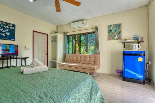 a bedroom with a bed and a couch and a window at Tachang Garden Cottage in Ban Tha Chang