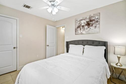 1 dormitorio con cama blanca y ventilador de techo en Opulent, Luxurious & Modern APT 7 Min From TX Med Center, en Houston