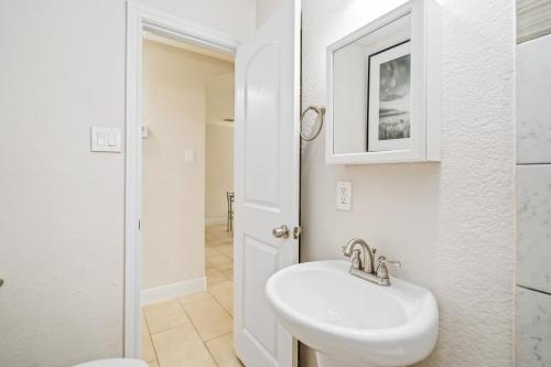 Baño blanco con lavabo y espejo en Opulent, Luxurious & Modern APT 7 Min From TX Med Center, en Houston