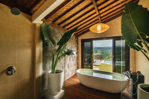 a bathroom with a bath tub and a potted plant at Patal Kikian Villa in Sidemen