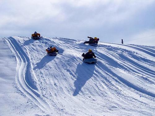 three people riding down a snow covered hill on snowboards at Kurohime Kogen Hotel in Shinano