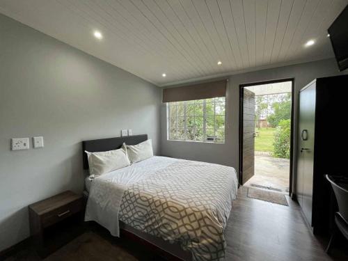 een slaapkamer met een bed en een groot raam bij Halleria Self Catering in White River