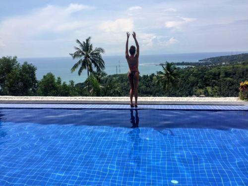 a woman standing on the edge of a swimming pool at Villa Umbrella Lombok in Senggigi 
