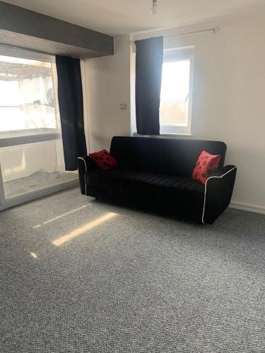 czarna kanapa w pokoju z oknem w obiekcie City View apartments w Londynie