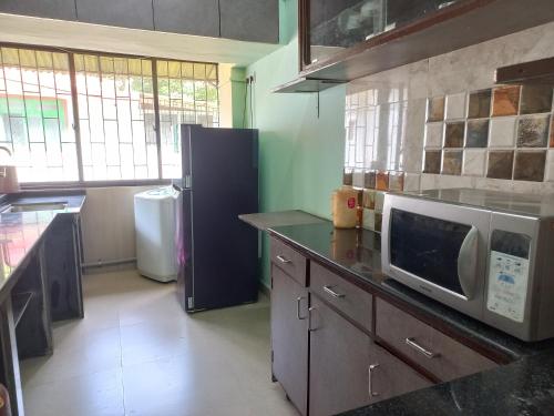 a kitchen with a refrigerator and a microwave on a counter at 2 Bhk Holiday home near Panjim city & Beaches in Panaji