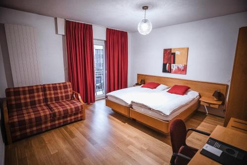 1 dormitorio con cama, sofá y ventana en Hôtel Elite, en Sion