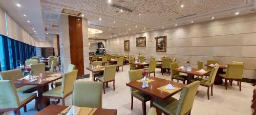 a restaurant with wooden tables and green chairs at Al safwah Tower one in Makkah
